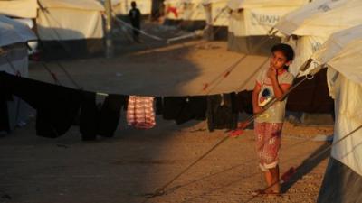 Girl standing in front of tent in refugee camp in Iraq