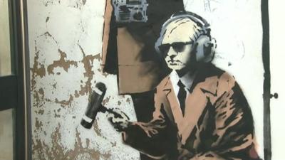 Section of Banksy work showing man with microphone and headphones