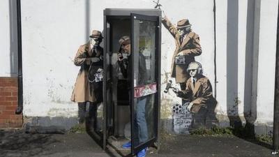 Man in phonebox with artwork on wall behind