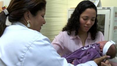 Nurse handing a mother her newborn baby