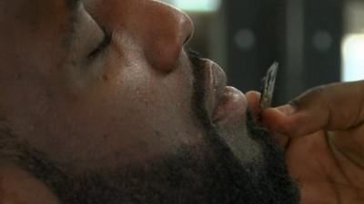 A footballer having his beard groomed at the barbers