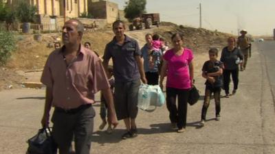 People walk away from Qaraqosh