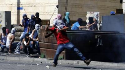 Palestinian hurling stone towards police