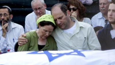 Avi and Rachel Frenkel embrace during the funeral of their son, Naftali Frenkel