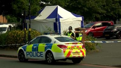 Police car and officer at scene of disorder