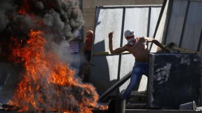 Masked Palestinian protesters throw stones towards Israeli police in East Jerusalem on 2 July 2014