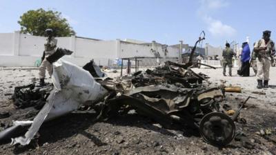 Somali government soldiers gather near the wreckage after a suicide car explosion near the Somali parliament building in Mogadishu