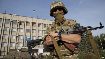 Soldier standing in front of government building flying Ukrainian flag in Sloviansk