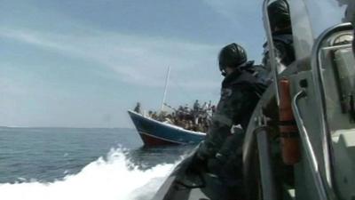 Archive footage of officials approaching boat of asylum seekers