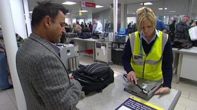 Airport security staff checking laptop