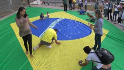 Brazilian fans sign the national flag