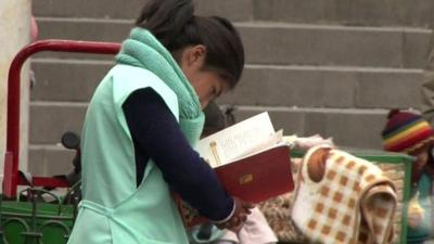 Bolivian child worker studying while she works