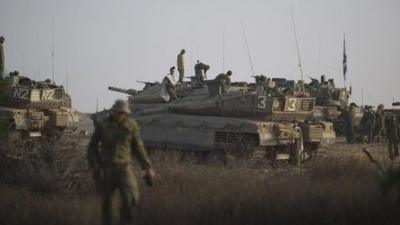 Israeli soldiers work on their tanks at a staging area near the Israel-Gaza Border, 9 July