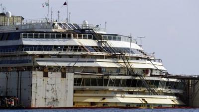 A view of the luxury cruise ship Costa Concordia, flanked by the two huge tanks that were used to put it afloat, on the tiny Tuscan island of Giglio, Italy, Monday, July 14, 2014