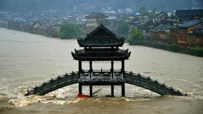 Buildings and a bridge are submerged by flood water at the Fenghuang Ancient Town on July 15, 2014