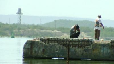 Two men on pier with Guantanamo Bay watch tower in background