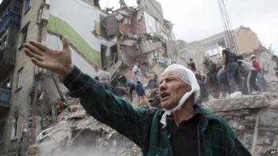 Man in front of badly damaged building