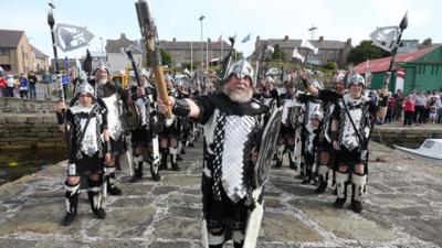 Alexander Johnson, dressed as a Viking, carries the Glasgow 2014 Queen's Baton through Lerwick on the Shetland Islands.