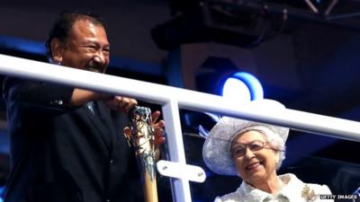 Prince Imran the CGF President attempts to retrieve the message from the baton as he presents it to Queen Elizabeth II