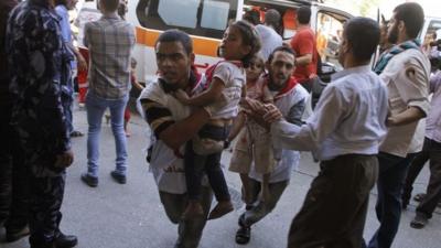 Palestinian medics run carrying children wounded in attack on UN shelter in Beit Hanoun