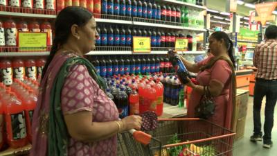 Indian women looking at fizzy drinks in a supermarket