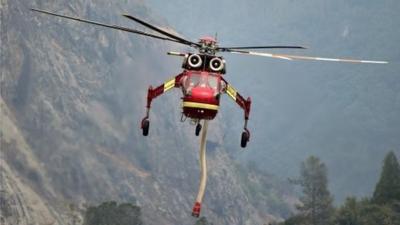 A firefighting helicopter flies in to siphon water out of the Merced River in order to fight the El Portal Fire in the Stanislaus National Forest and Yosemite National Park in California