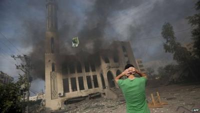 A man stands before a ruined mosque in Gaza City, 29 July