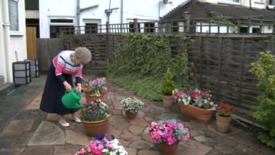 Jean Hall watering plants in her garden