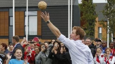 Prince Harry plays a game during a visit to the Commonwealth Games Village