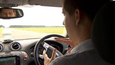 Man sitting in driving seat of driverless car