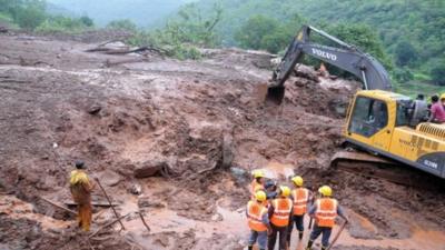 A handout photograph from the Maharashtra state government shows diggers working at the site of a landslide in the village of Malin in Pune