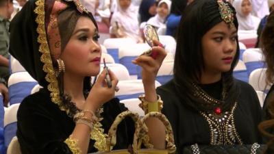 Smartly dressed woman applying lipstick and sitting with a friend