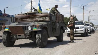 Ukrainian government army's soldiers stand guard next to the cars of convoy of the OSCE mission in Ukraine