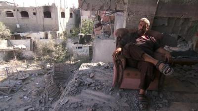 man sits in remains of his house