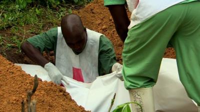 Four-month-old Ebola victim from the affected village of Gueckedou, Guinea, is buried by aid workers