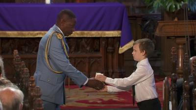 Man handing candle to small boy as part of Glasgow Cathedral commemorative service