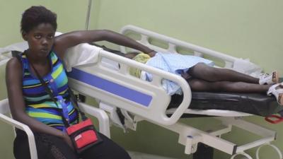 Child on hospital trolley with woman by her side