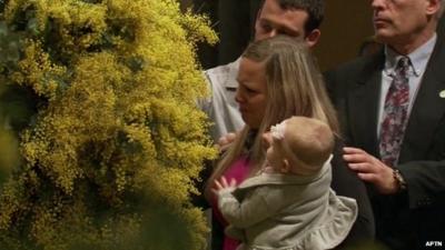 Woman mourner with baby being comforted as she takes part in MH17 memorial service in Melbourne's St Patrick's Cathedral