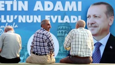 People sit in front of campaign poster