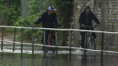 cyclists riding through flood water