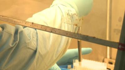 Hands dropping liquid into test tubes