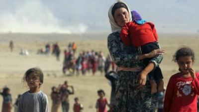 Displaced people from the minority Yazidi sect, fleeing violence from forces loyal to the Islamic State in Sinjar town, walk towards the Syrian border