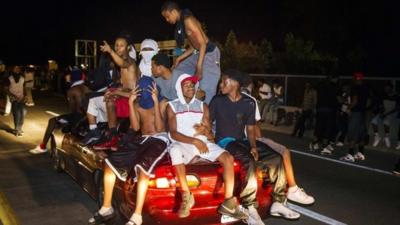 Protesters chant as they ride on a car during a peaceful demonstration as communities continue to react to the shooting of Michael Brown in Ferguson, Missouri August 14, 2014