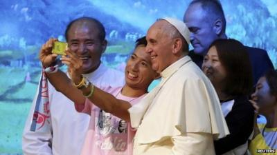 Pope Francis posing for photograph with young man