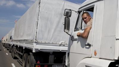 A truck driver looks out of the cabin of his vehicle which forms part of an aid convoy destined for Ukraine