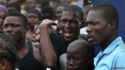 A crowd urges people in an Ebola isolation centre to come out after a mob opened the gates the facility