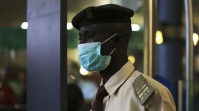 An immigration officer wears a face mask at an airport in Abuja