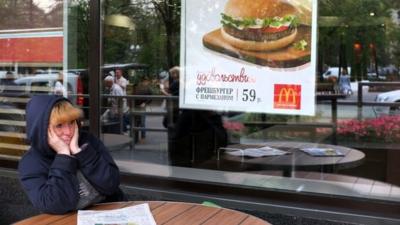 A woman sits a table of a closed McDonald"s restaurant, the first to be opened in the Soviet Union in 1990, in Moscow on August 21, 2014