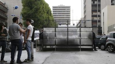 People chat in front of fences set up by French riot police officers as they stand guard in front of the synagogue in Sarcelles, a suburb north of Paris, on July 20, 2014, after clashes following a pro-Palestinian demonstration denouncing Israel"s military campaign in Gaza and showing support to the Palestinian people