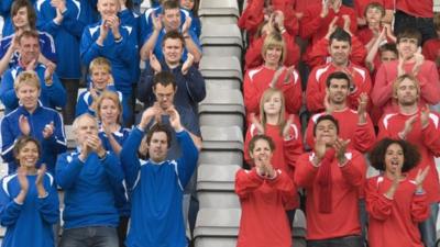 Football fans standing and clapping